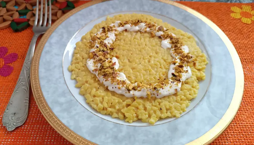 Un cremoso risotto con robiola e zafferano, guarnito con pistacchi tritati, pronto per essere gustato.