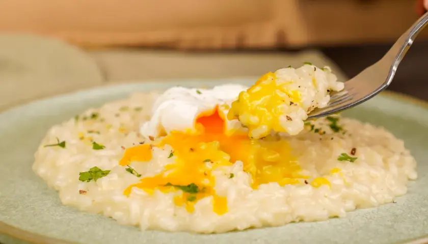 Un cremoso risotto con un uovo in camicia, il cui tuorlo dorato si riversa sul riso. Un piatto invitante e gustoso.