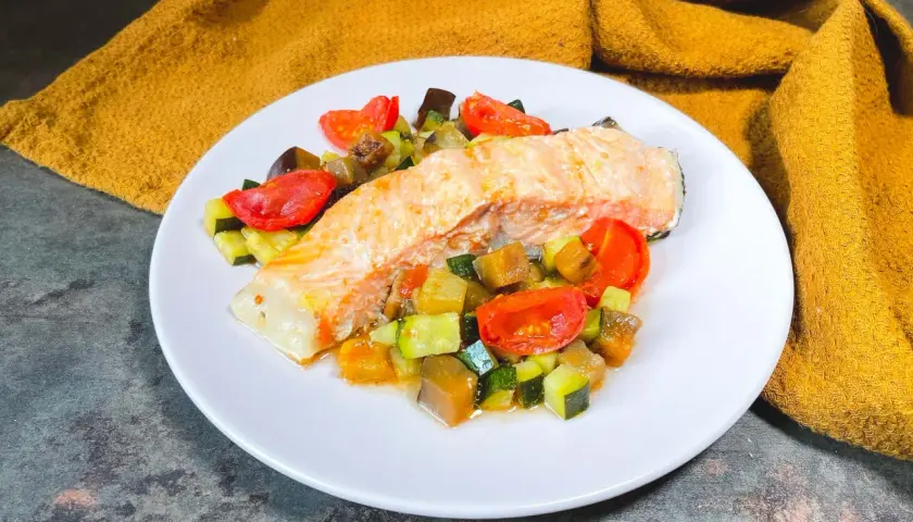 Filetto di salmone su un letto di verdure miste, un'ottima idea su cosa abbinare al salmone per un pasto leggero e saporito.