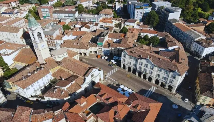 Vista aerea di un paese con campanile, tetti rossi e palazzi storici. Un luogo dove ci sono molti **broni cosa vedere**.