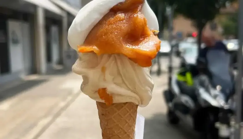 Cono con gelato artigianale, bianco e arancione, con un tocco di gelato contadino. Perfetto per una passeggiata estiva.