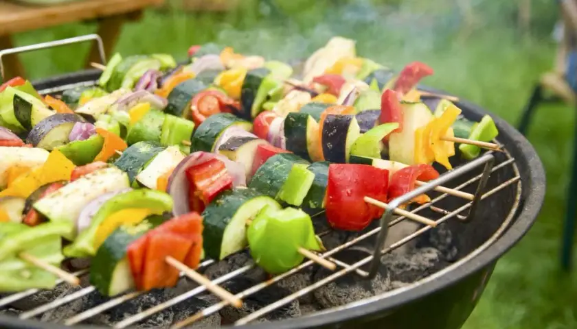 Spiedini colorati di verdure fresche, pronti per una deliziosa grigliata vegetariana. Zucchine, peperoni, melanzane e cipolle cuociono sulla brace.
