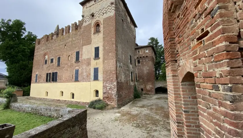 Antico castello in mattoni rossi, un gioiello da scoprire nella Lomellina, con torri merlate e un cortile interno.