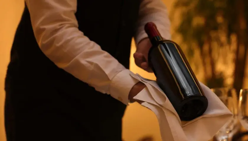 Cameriere serve un vino costoso, con eleganza, su un tovagliolo bianco.