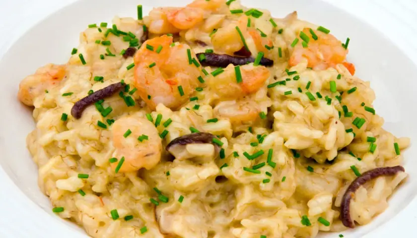 Un cremoso risotto funghi e gamberetti, guarnito con erba cipollina fresca.