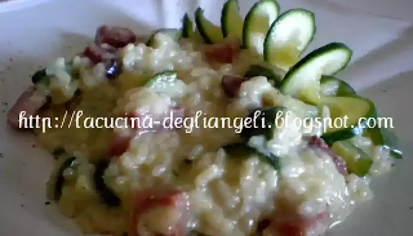 Risotto cremoso con robiola e speck croccante, guarnito con zucchine fresche. Un piatto delizioso e invitante.