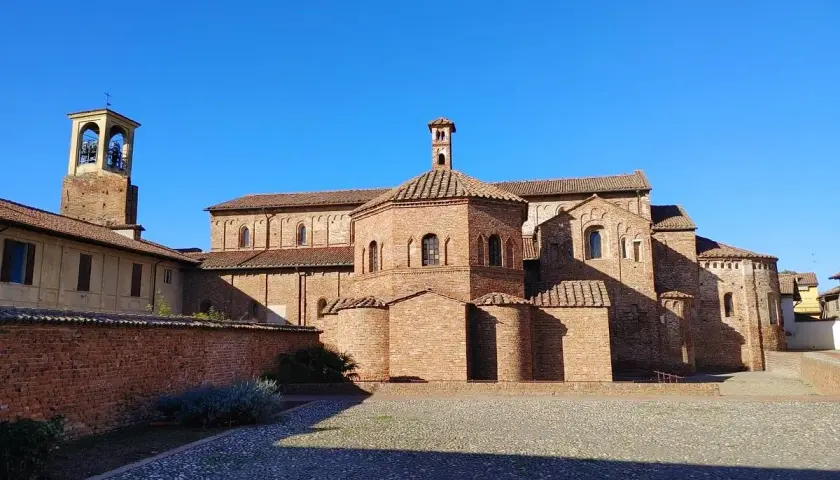 Lomello cosa vedere: la Basilica di San Magno, un gioiello romanico in mattoni rossi, con il suo campanile svettante sotto un cielo azzurro.