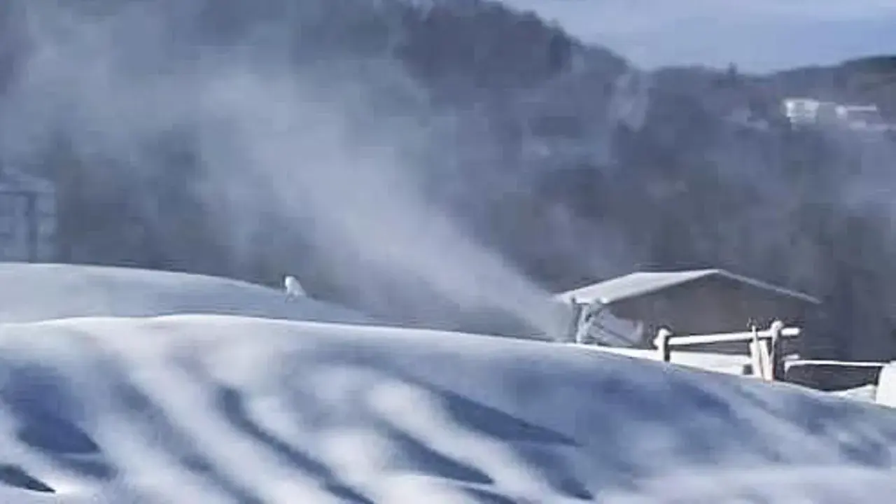 Neve artificiale sul Monte Penice, con un cannone spara-neve in azione e un rifugio sullo sfondo.