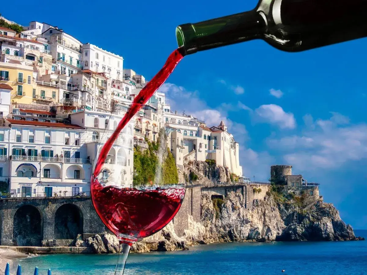 Un bicchiere di vino rosso si riempie con vista sulla costa amalfitana, un assaggio dei vini Campania.