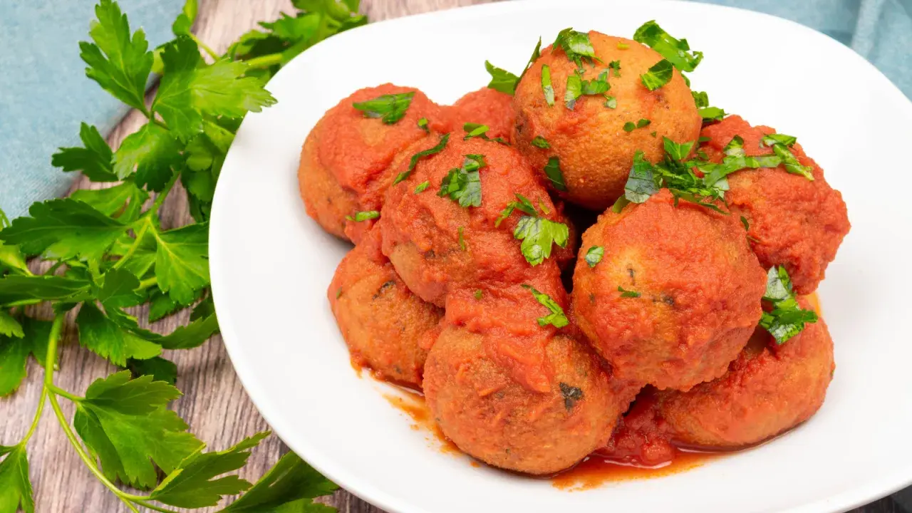 Pallotte cacio e ova, gustose polpette in salsa di pomodoro, guarnite con prezzemolo fresco.