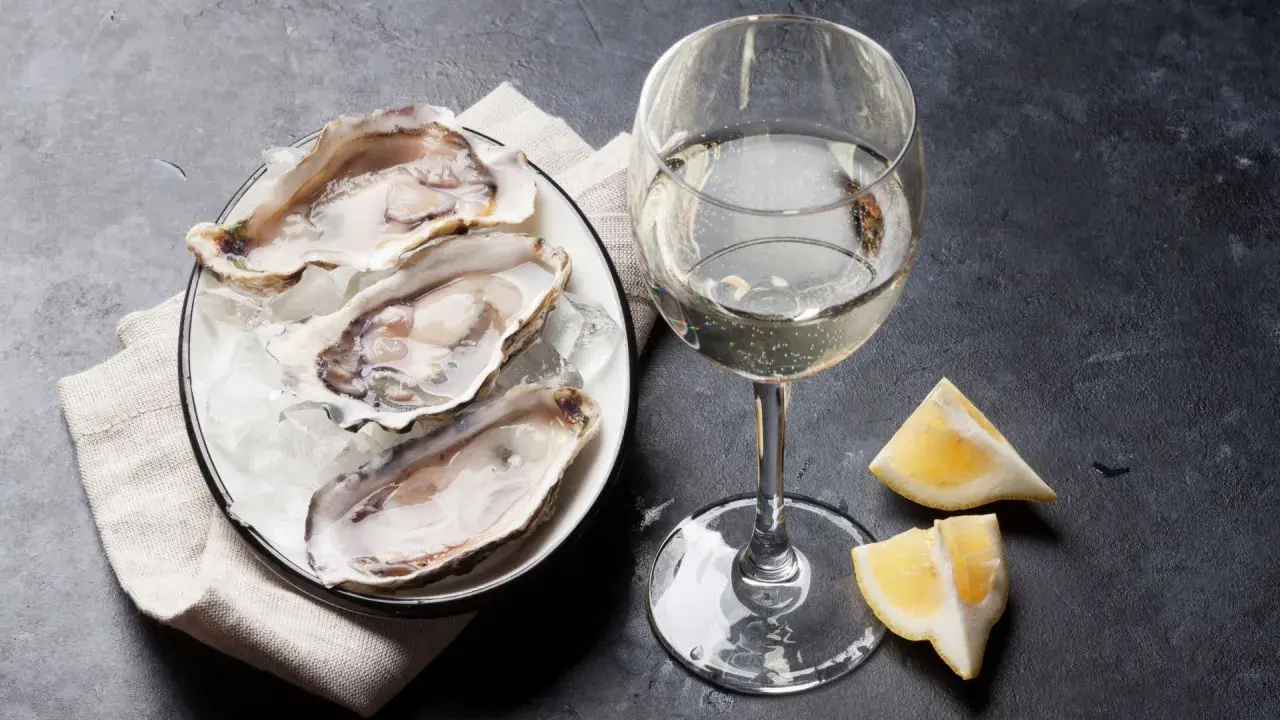 Ostriche fresche su ghiaccio, un bicchiere di champagne frizzante e spicchi di limone. Un'immagine che evoca lusso e piacere.