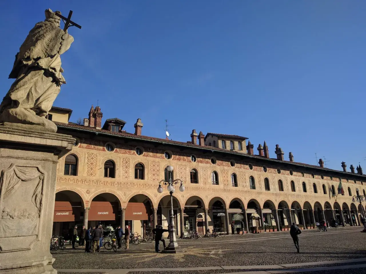 Statua e portici decorati in Piazza Ducale, un luogo imperdibile tra le cose da vedere a Vigevano.
