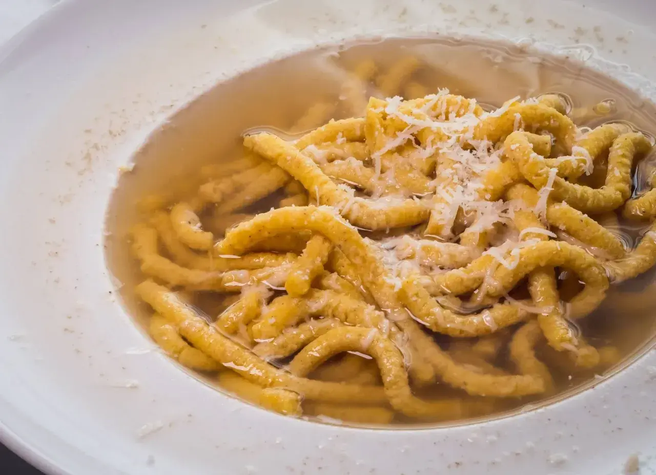 Passatelli in brodo, un classico dei cibi tipici dell'Emilia Romagna, con abbondante parmigiano grattugiato.