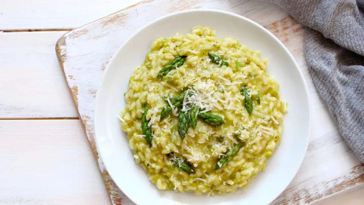 Risotto cremoso con asparagi freschi e robiola, guarnito con parmigiano grattugiato. Un piatto primaverile delizioso.