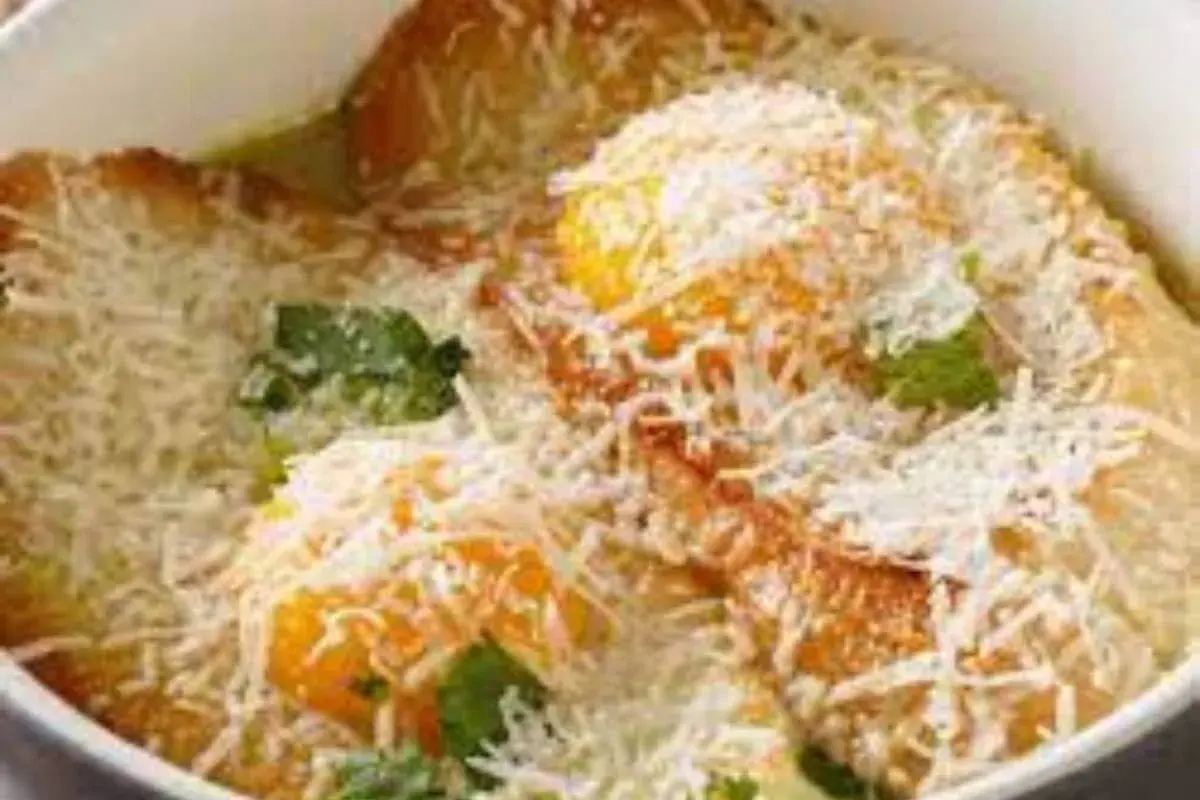 Piatto tipico Pavia: tortelli di zucca dorati, ripieni di formaggio e guarniti con erbe fresche e abbondante parmigiano grattugiato.