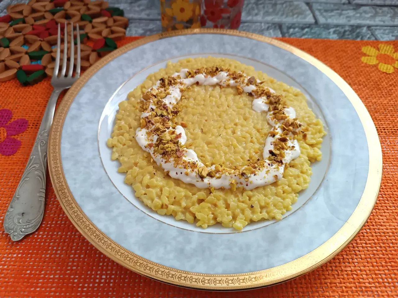 Un cremoso risotto con robiola e zafferano, guarnito con pistacchi tritati, pronto per essere gustato.