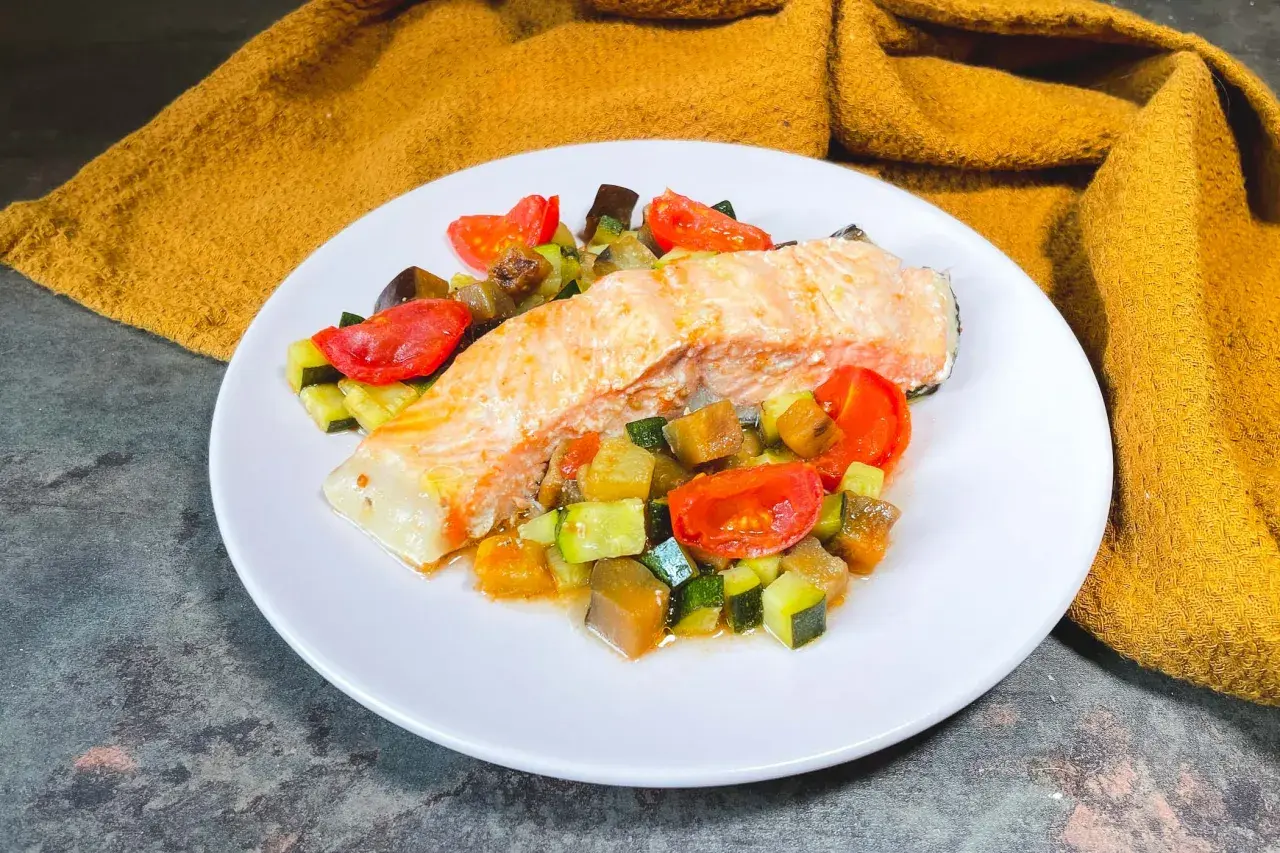 Filetto di salmone su un letto di verdure miste, un'ottima idea su cosa abbinare al salmone per un pasto leggero e saporito.
