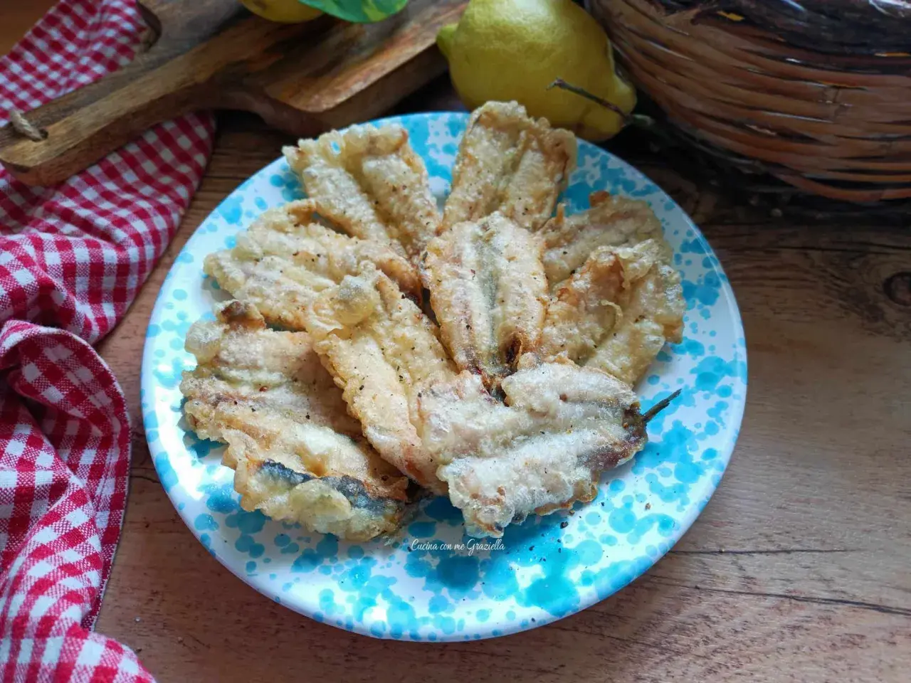 A plate of golden fried anchovies with a light, crispy coating, seasoned with pepper.