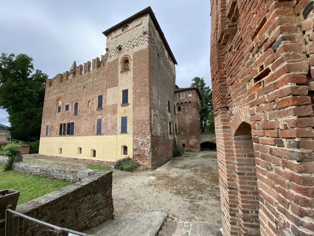 Antico castello in mattoni rossi, un gioiello da scoprire nella Lomellina, con torri merlate e un cortile interno.