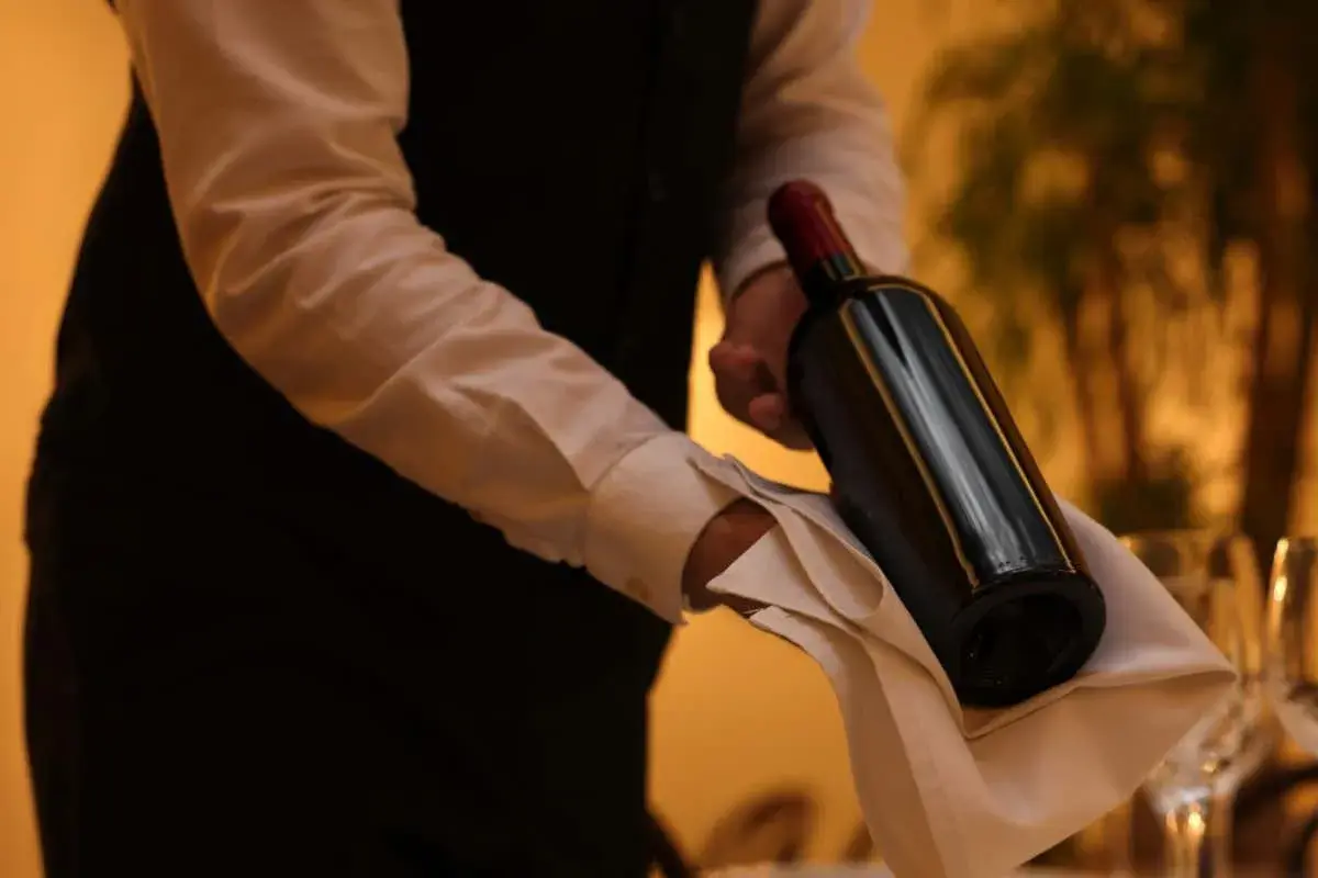 Cameriere serve un vino costoso, con eleganza, su un tovagliolo bianco.