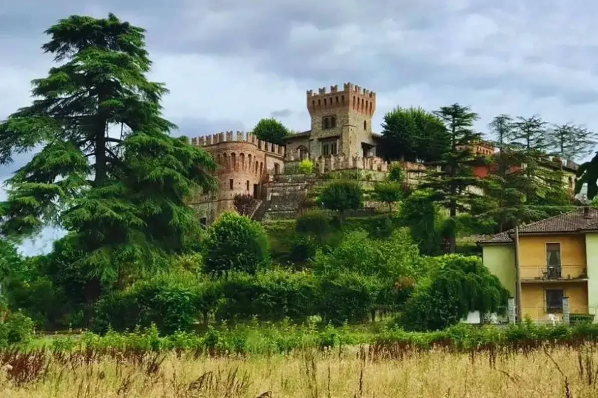 La rocca di Montalfeo, un castello medievale circondato da alberi secolari e vegetazione lussureggiante, domina la collina.