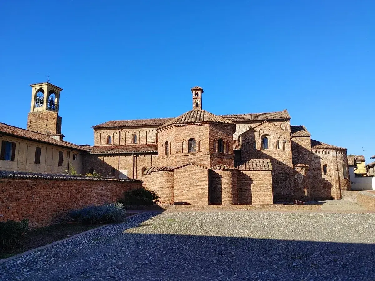 Lomello cosa vedere: la Basilica di San Magno, un gioiello romanico in mattoni rossi, con il suo campanile svettante sotto un cielo azzurro.