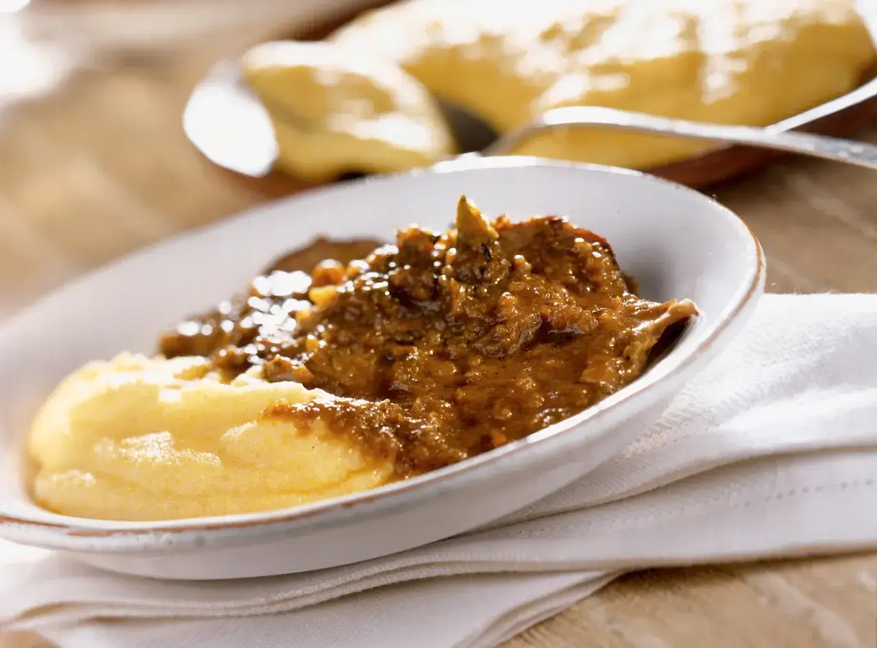 Un piatto invitante di brasato al buttafuoco, succulento e saporito, servito su un letto di morbida polenta gialla.