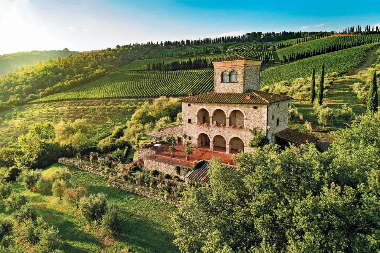 Un casale in pietra con torretta, circondato da vigneti e uliveti, incarna la bellezza del super tuscany.