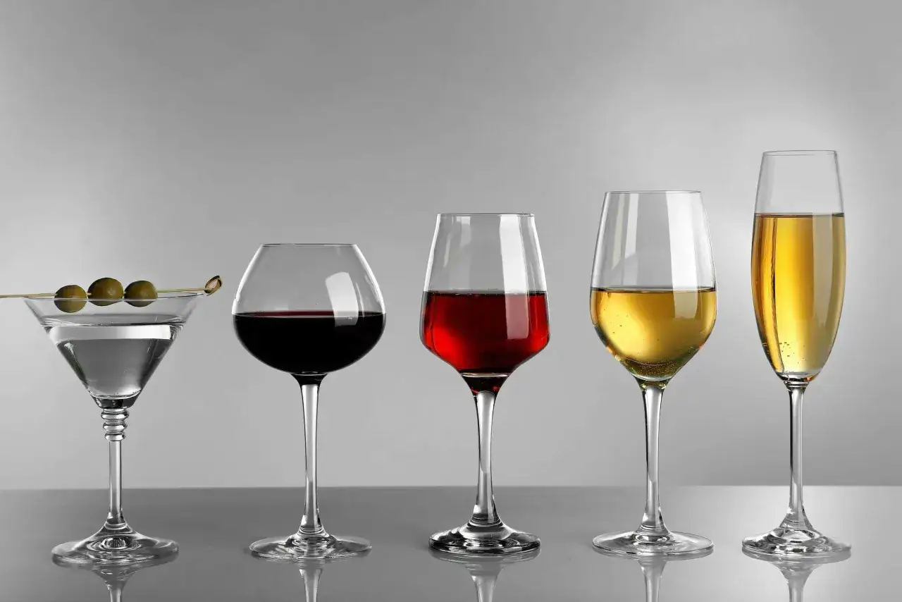 Cinque bicchieri: un martini con olive, un calice di vino rosso, uno con vino rosso più chiaro, uno con vino bianco frizzante e uno con spumante.