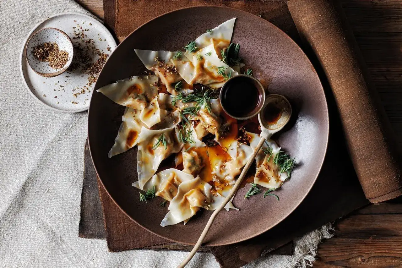 Jiaozi succulenti e profumati, conditi con salsa e erbe aromatiche, pronti per essere gustati con delle bollicine.