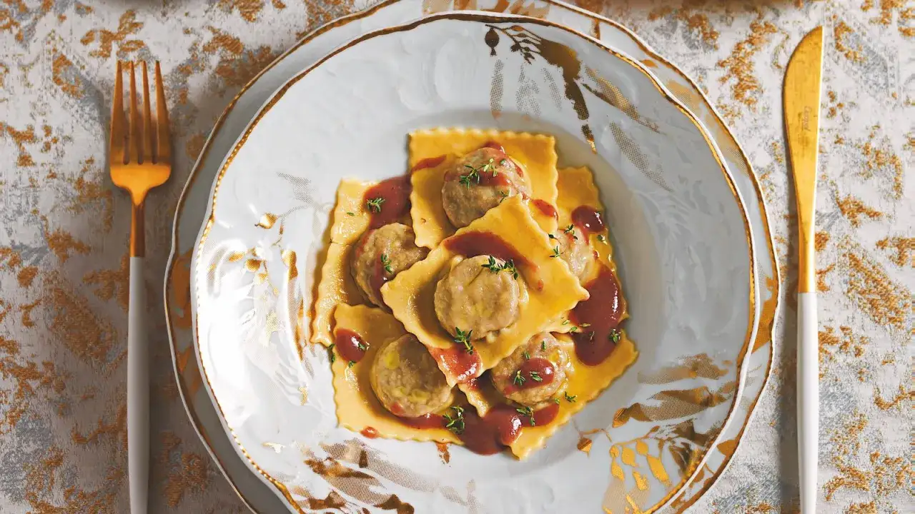 Agnolotti al brasato, pasta fresca ripiena di carne, condita con sugo e timo, servita su un piatto elegante.