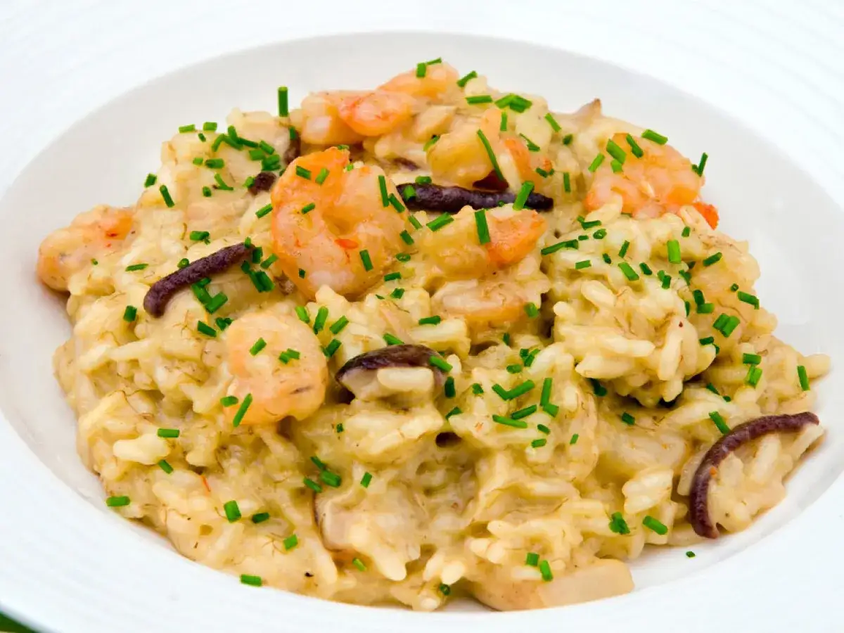 Un cremoso risotto funghi e gamberetti, guarnito con erba cipollina fresca.