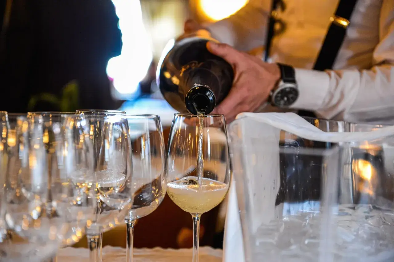 Un sommelier versa il migliore vino bianco in un calice, creando un'atmosfera di eleganza e attesa per un'esperienza gustativa indimenticabile.