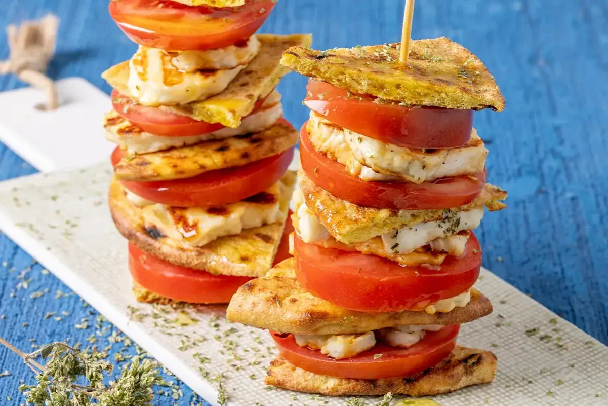 Torri di grigliata vegetariana con pomodoro fresco e formaggio grigliato, condite con erbe aromatiche.