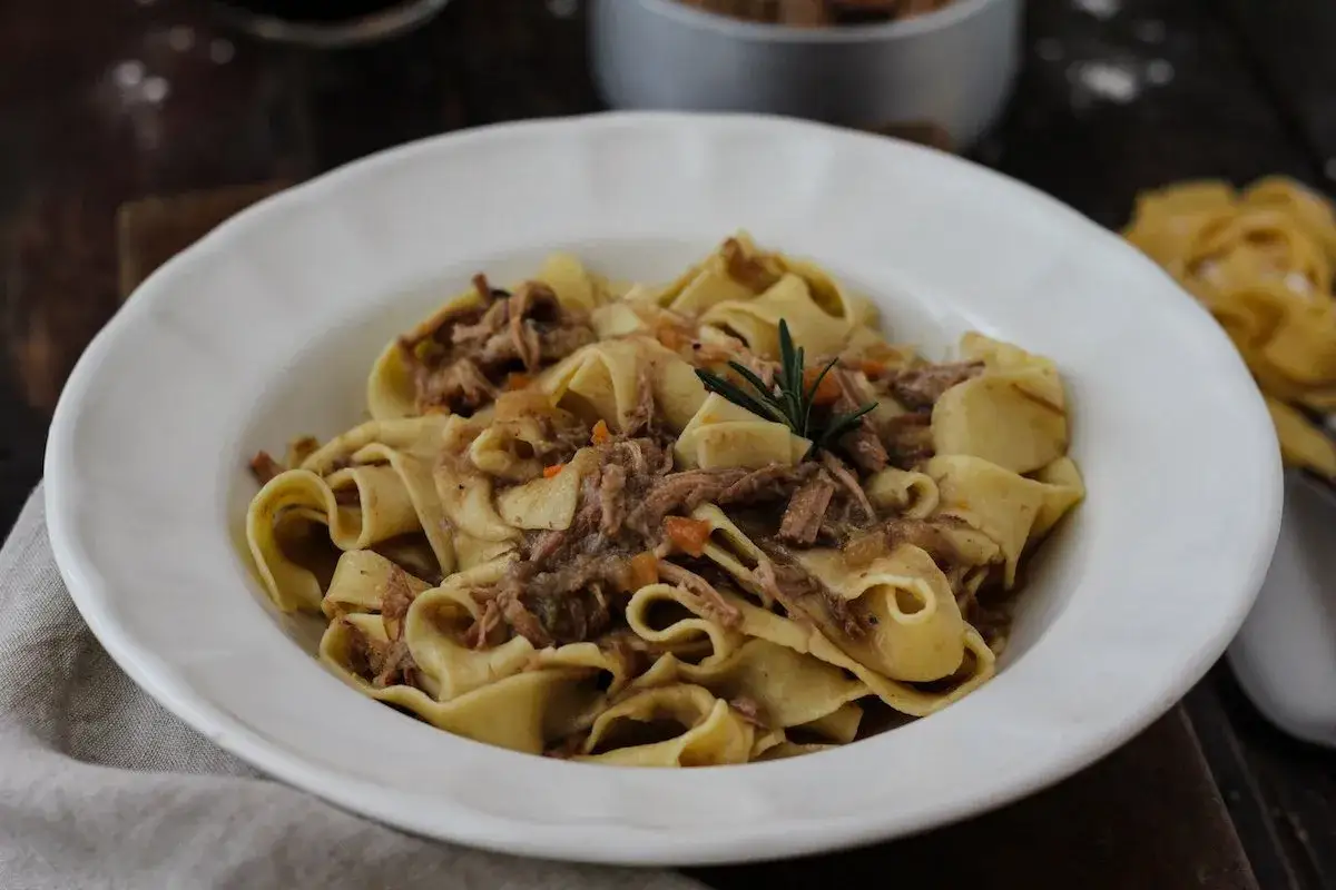 Pappardelle con rag&ugrave; di carne, un classico dei primi piatti di carne, guarnite con rosmarino.