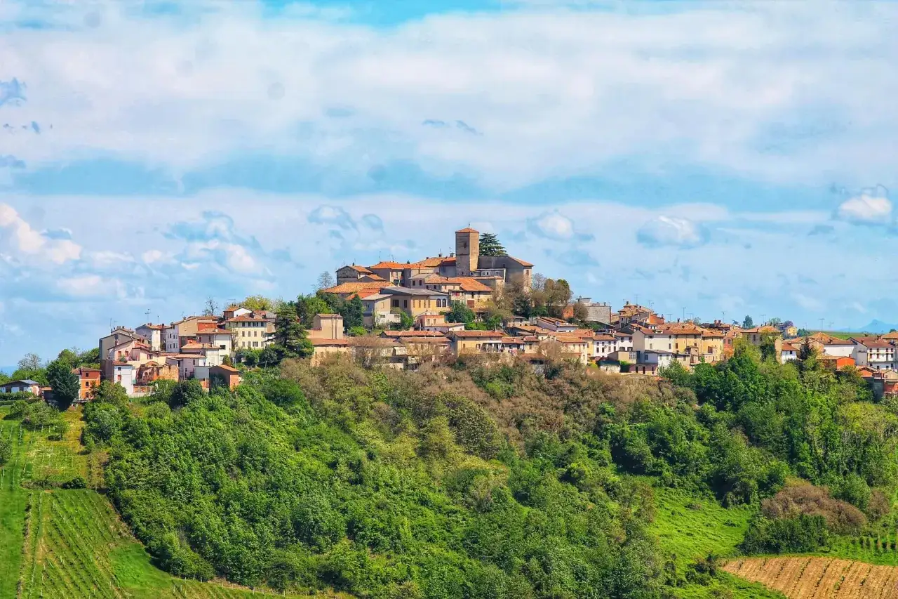Borgo collinare con case dai tetti rossi e una torre, circondato da verde. Un luogo incantevole dove scoprire cosa vedere.