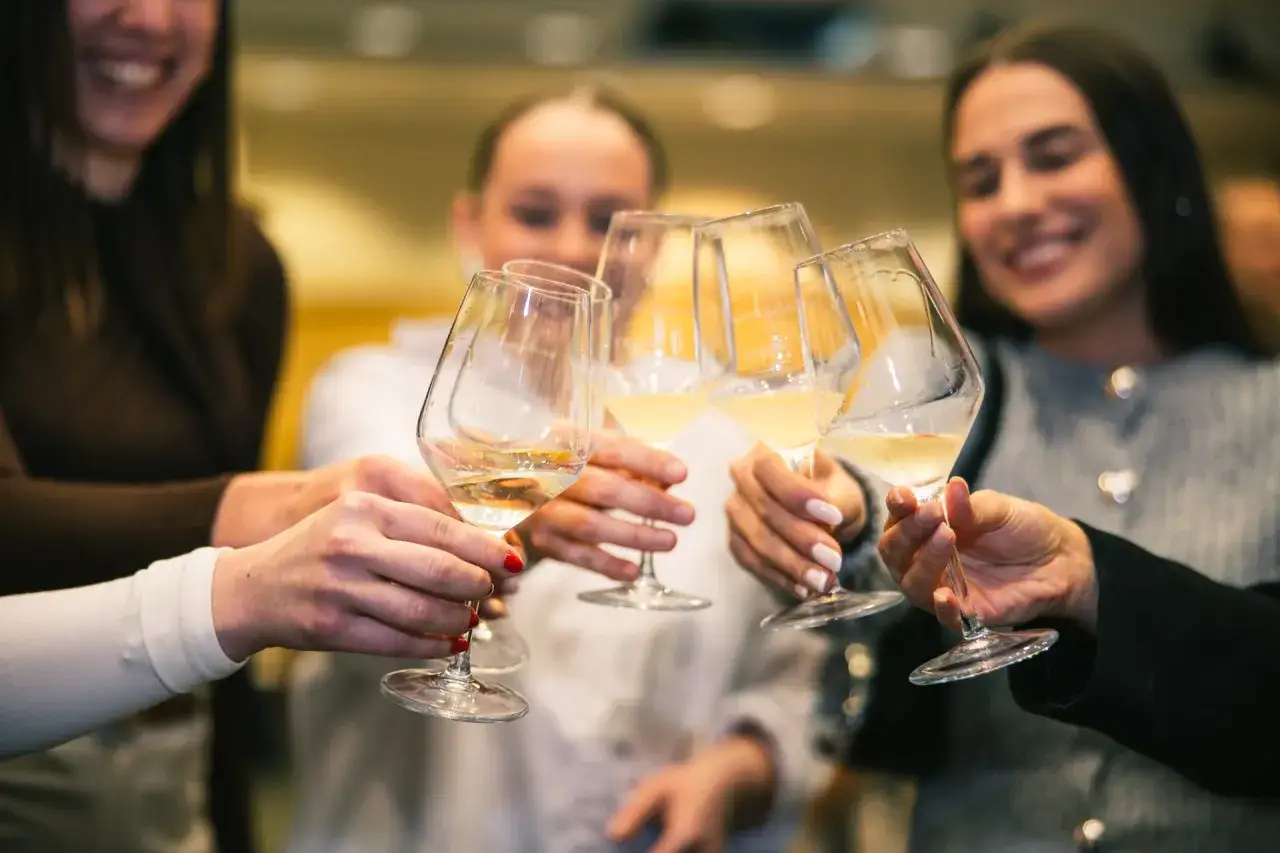 Un brindisi con calici di malvasia istriana, le mani si avvicinano per celebrare un momento di gioia.