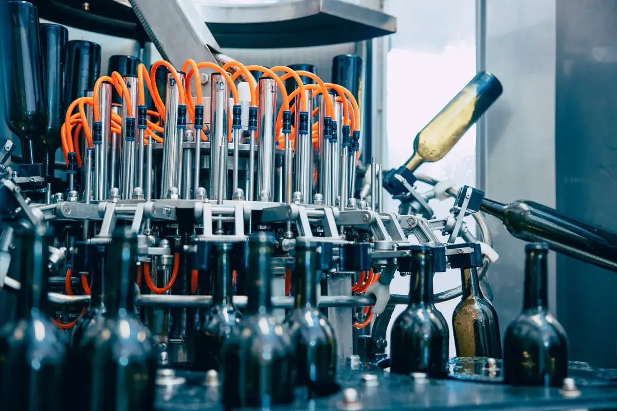 Macchine per la vinificazione in azione: bottiglie di vetro in lavorazione su una linea di imbottigliamento automatizzata.