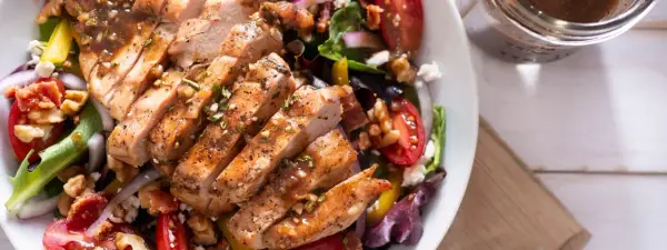 Deliziosa insalata estiva gourmet con pollo grigliato, pomodorini, noci e formaggio feta. Perfetta per un pasto leggero e saporito.