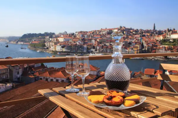 Un bicchiere di vino porto e dolci su un tavolo con vista sulla città di Porto, Portogallo.
