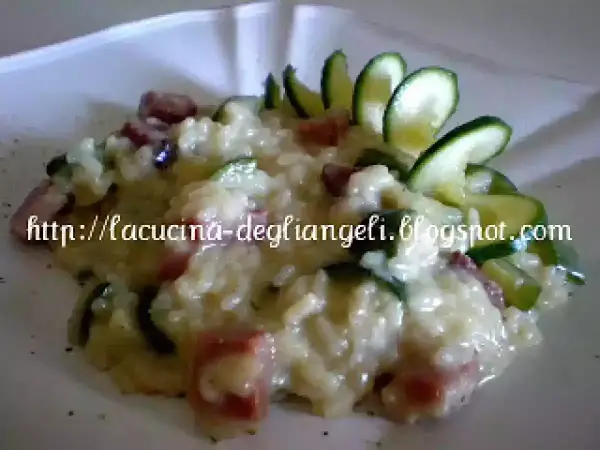 Risotto cremoso con robiola e speck croccante, guarnito con zucchine fresche. Un piatto delizioso e invitante.